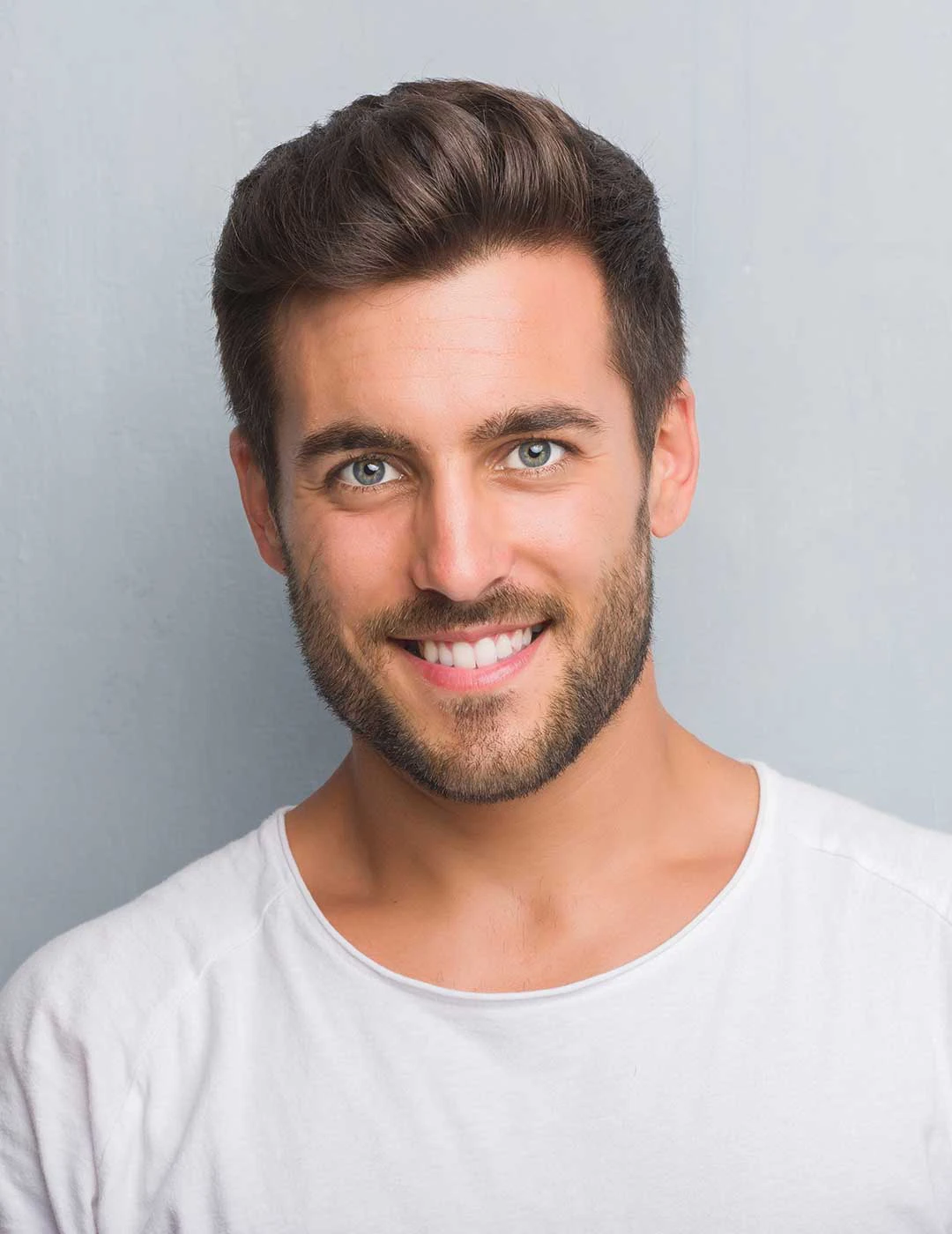 Handsome man smiling confidently, showcasing a natural-looking smile after receiving inlays and onlays dental treatment.